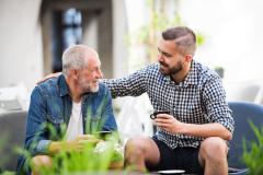 pere et fils prenant un café sur la terrasse de la maison familiale