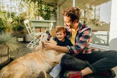 Un père et son fils jouent avec leur chien sur la terrasse