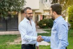 Deux hommes se serrent la main dans un jardin 