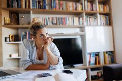 Femme installée à la table dans son salon s'interroge