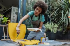 Femme en train de peindre une chaise pour donner une seconde vie à son meuble