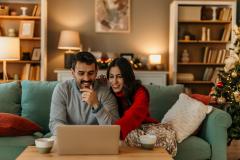 Couple dans son salon décoré pour les fêtes regarde son ordinateur