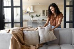 femme arrange des coussins sur son canapé