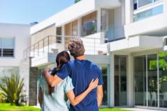 Un couple regarde la maison qu'il convoite de l'extérieur.