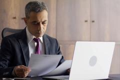 Un homme de loi assis à son bureau examine un acte officiel au format papier
