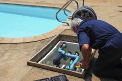 Un homme effectue des réglages sur le système de filtration de sa piscine