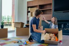 Un père et sa fille font des cartons de déménagement dans le salon. 