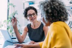 Un agent immobilier femme discute au bureau avec sa cliente portant une blouse jaune.