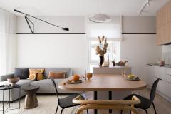 Salon avec canapé gris et table à manger au premier plan.