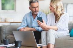 Femme sur le canapé montre à son époux son téléphone où il peut lire des infos sur la trêve hivernale
