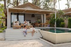 Un couple et ses deux enfants profitent d'une belle villa avec petite terrasse et piscine. 