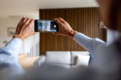 Une femme tourne une vidéo de son appartement avec son téléphone.