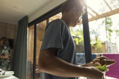 Jeune homme qui sert les croissants dans un mobil-home de vacances. 