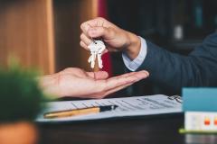 estate agent giving house keys to woman and sign agreement in office