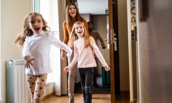 Famille qui sourit et qui rentre dans une maison