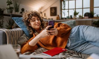 jeune femme sur son téléphone allongé sur son canapé