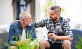 pere et fils prenant un café sur la terrasse de la maison familiale