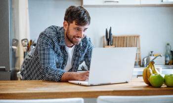 jeune-homme-fait-des recherches-sur-son-ordinateur-depuis-la-cuisine