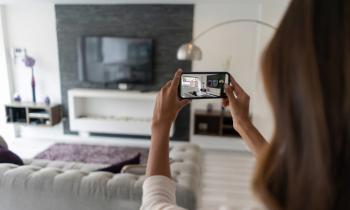 Un agent immobilier femme filme dans le salon avec son téléphone mobile.