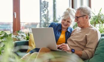 couple de personnes âgées regarde son ordinateur depuis le canapé