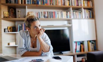 Femme installée à la table dans son salon s'interroge