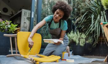 Femme en train de peindre une chaise pour donner une seconde vie à son meuble