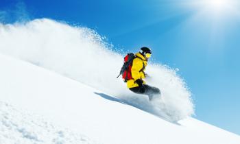 Snowboarder avec doudoune jaune dans les Alpes