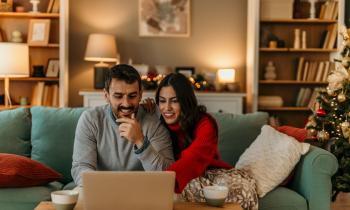 Couple dans son salon décoré pour les fêtes regarde son ordinateur