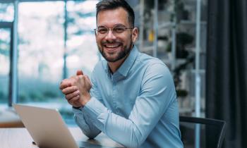 Un agent immobilier souriant devant son ordinateur. 