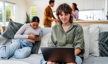 jeune femme regarde son ordinateur dans le salon de sa colocation