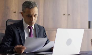 Un homme de loi assis à son bureau examine un acte officiel au format papier