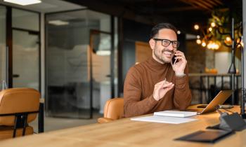 Professionnel qui parle au téléphone dans son bureau aux tons chauds.