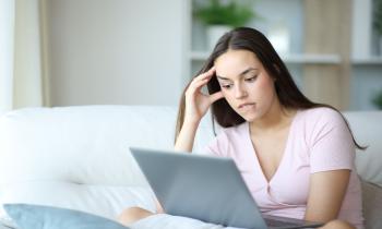 jeune femme regarde son ordinateur l'air inquiet