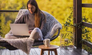 femme-regarde-son-ordinateur-sur-le-canape-de-son-balcon