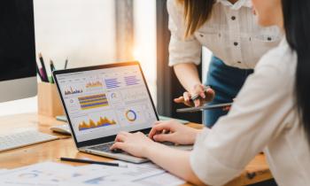 Deux femmes consultent les tableaux de bord de leur CRM sur un ordinateur. 