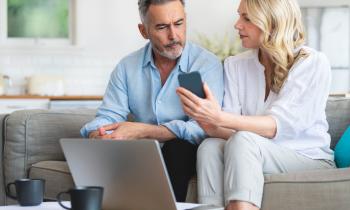 Femme sur le canapé montre à son époux son téléphone où il peut lire des infos sur la trêve hivernale
