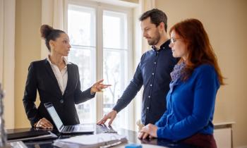 Un couple échange dans le salon avec l'agent immobilier en charge de la vente de son bien immobilier