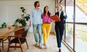 Un agent immobilier femme fait visiter un beau logement lumineux à un couple. 
