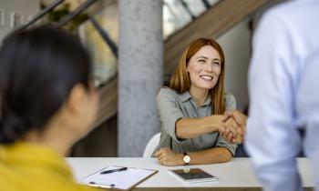 Agent immobilier femme souriante qui serre la main de son client. 