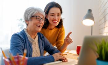 Une mère et sa fille majeure discutent et regardent l'ordinateur sur le bureau. 