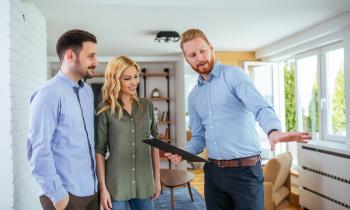 Un agent immobilier expert fait visiter un appartement à un couple homme, femme. 
