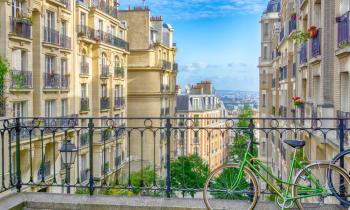 Vélo attaché à un grillage en hauteur, avec vue imprenable sur Paris et ciel bleu. 