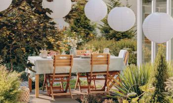 Vue sur une terrasse avec table de repas et guirlande lumineuse