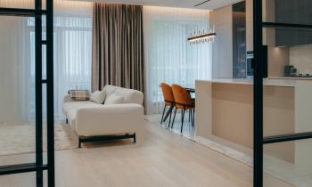 Petit appartement de luxe et décoration épurée avec canapé blanc et portes vitrées. 