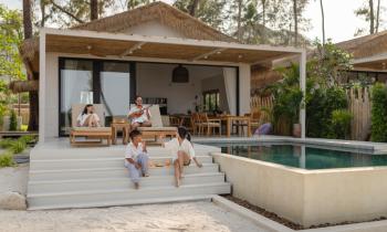 Un couple et ses deux enfants profitent d'une belle villa avec petite terrasse et piscine. 