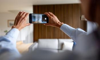 Une femme tourne une vidéo de son appartement avec son téléphone.