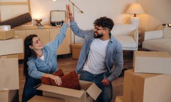 Couple qui se tape dans la main, dans son nouveau salon, entouré de cartons.