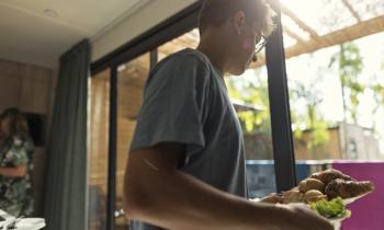 Jeune homme qui sert les croissants dans un mobil-home de vacances. 