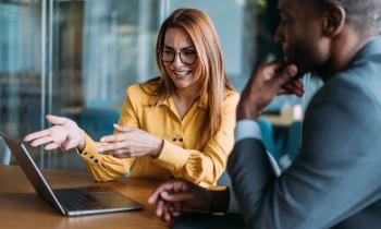 Un investisseur homme en veste grise écoute son conseiller bancaire femme en veste jaune. 