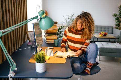 Une jeune femme étudie sur son bureau, dans son studio étudiant.